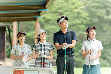 Male and female golfers taking golf lessons at a golf course