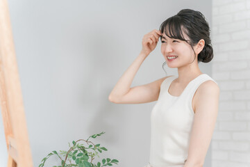 A smiling Japanese woman checking her bangs and hair style