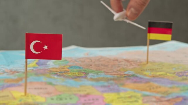 Toy airplane flying from Germany to Turkey over world map, symbol summer vacations, diaspora travel, charter airlines and busy Europe to Turkey air corridor.