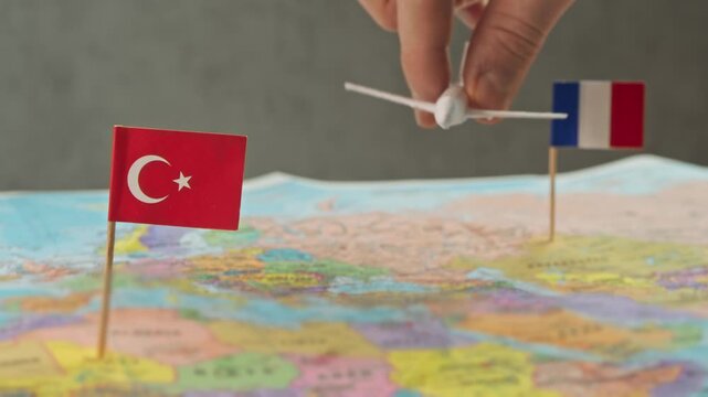 Toy airplane flying from France to Turkey over colorful world map, symbol tourism flights, city breaks, business trips and international air connection.