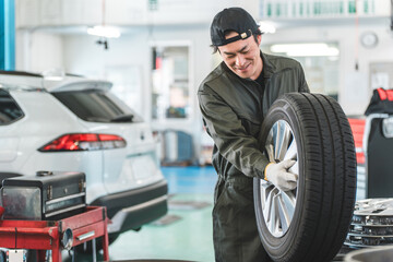 Male mechanic carrying tires at an auto repair shop (physical labor, hard work, heavy, back pain)