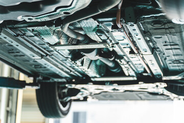 The undercarriage of a car lifted up at a repair shop