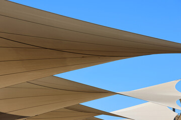 Beige shade sails canopy against a blue sky abstract background