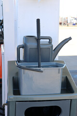 Car cleaning equipment with a bucket, watering can and squeegee at a gas petrol station