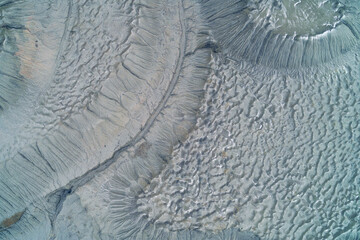 Abstract gray clay texture of industrial wasteland with crater depressions and dry soil bubbles, desolate earth background aerial top down view