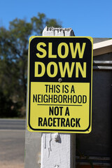 Slow Down - This Is A Neighborhood Not A Racetrack sign attached to a wooden post