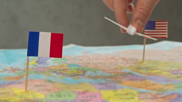 Toy airplane near United States and France flags on world map, symbol long haul routes, alliance hubs, tourism demand and competition in France transatlantic air travel market.