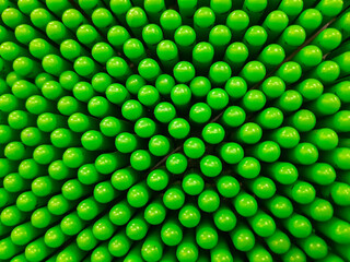 Abstract background of green pin art toy with rounded pins forming a dense geometric pattern. Close up texture with depth, symmetry, and creative visual effect