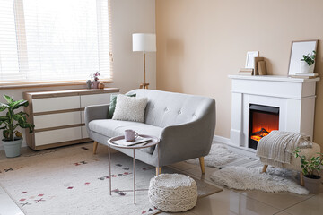 Naklejka premium Interior of living room with grey sofa, commode and fireplace