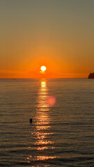 A stunning sunset over a calm ocean with a vibrant orange sky. the silhouette in the water adds depth and tranquility, capturing the essence of peaceful moments.