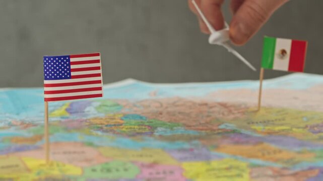 Toy airplane flying from Mexico to United States across political world map, symbol resort tourism, work travel, visiting relatives and busy North America air routes.