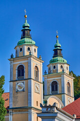 Obraz premium Clock and Bell towers with copper dome of the St. Nicholas Catholic church in the city center of Ljubljana, Central Slovenia, Europe