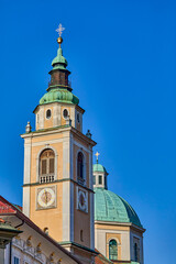 Obraz premium Clock and Bell towers with copper dome of the St. Nicholas Catholic church in the city center of Ljubljana, Central Slovenia, Europe