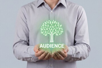 Businessman holding glowing tree icon with audience text representing marketing growth and community