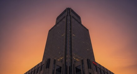 Imposing contemporary skyscraper dominates the frame against a warm sunset sky.