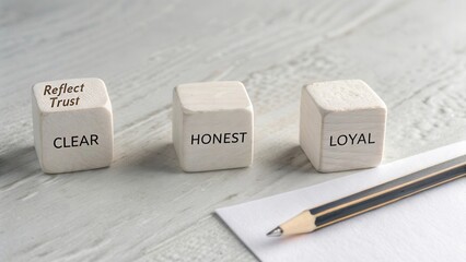 Inspirational wooden blocks displaying words clear, honest, loyal on a light wooden surface with a pencil and paper