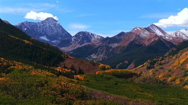 Morning sunny blue sky snowy 14er Capitol Peak creek trail wilderness Aspen Snowmass Colorado aerial drone golden aspen trees grove White River Forest Elk Range Rocky Mountains circle right parallax