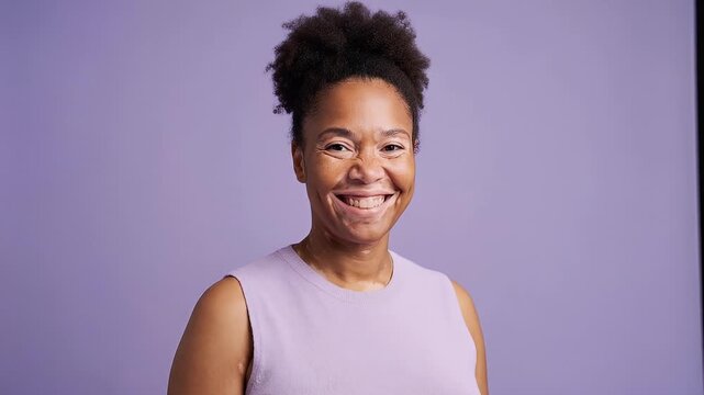 Happy black woman with vitiligo looking at camera and smiling on a purple studio background