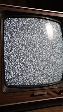 Vintage TV with screen static filling its dark wooden frame, with a close-up angle