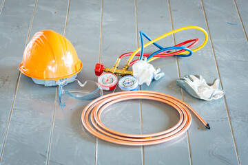 Air Conditioning Components: An array of tools and protective gear essential for the maintenance and repair of air conditioning units is neatly arranged on a concrete surface.