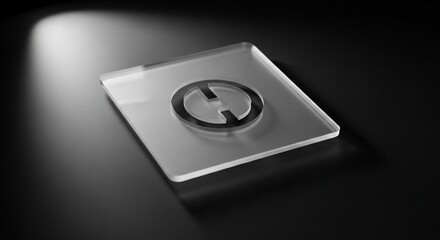 A clear rectangular plaque with a circular, stylized logo illuminated by a spotlight on a dark, reflective surface.