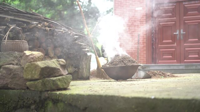 Rural courtyard with incense burner emitting smoke near red wooden door and stone steps