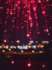 Vibrant Bokeh Rain of Shimmering Red and Magenta Hearts, Abstract Romantic Background with Defocused City Lights.