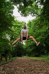 Energetic male athlete  jumps very high on running track with positive enthusiastic look on his face