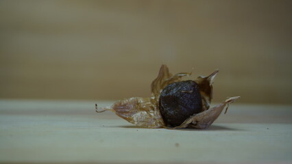 Pile of Single Clove Black Garlic, Allium sativum on Wood Background