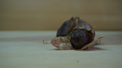 Pile of Single Clove Black Garlic, Allium sativum on Wood Background