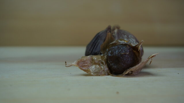 Pile of Single Clove Black Garlic, Allium sativum on Wood Background