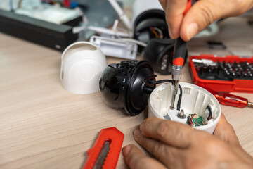 Close-up hand of man using screwdriver to repairing a wireless CCTV camera.