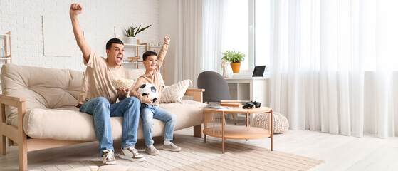 Happy father and his little son with popcorn watching football game at home © Pixel-Shot