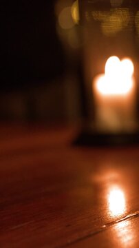 Soft Out of Focus Candle Flame Glowing on Wooden Table at Night
