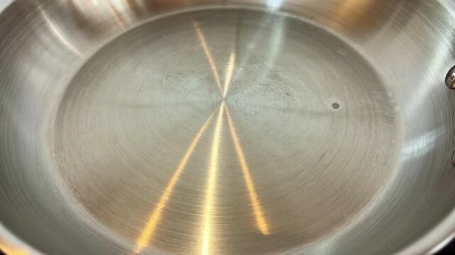 Oil poured into a hot steel pan, shimmering heat, kitchen cooking prep, close-up