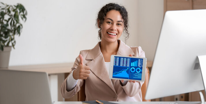 Young African-American QA engineer holding tablet computer with diagrams and showing thumb-up in office