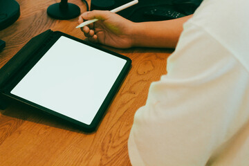 A businessman using digital tablet with blank white screen at wooden desk, productive work from home and remote office mockup concept.