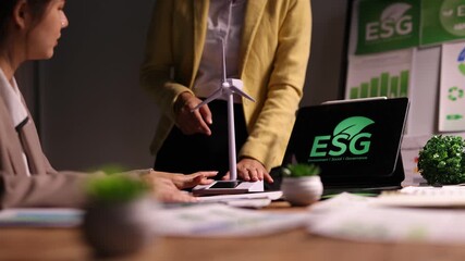 Businesswoman in a late-night meeting discussing ESG principles, presenting a wind turbine model for sustainable clean energy. - Powered by Adobe