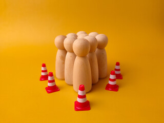 Conceptual stock photo of wooden figures surrounded by miniature traffic cones