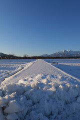眩しい日差しが照らす真っ白な雪道と冬の山々