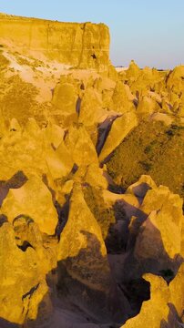 Vertical video. Goreme, Nevsehir, Turkey. Aerial view of Devrent Valley geological wonders showing wind erosion patterns and colorful rock strata at dusk.. Aerial View, Departure of the camera. Rich 