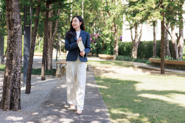 Fototapeta premium Young businesswoman walking outdoors carrying tablet smiling