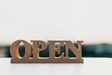 Open sign wooden letters with blurred background and copy space, symbolizing business opening, opportunity, welcome, and new beginning. Ideal for retail, startup, marketing, and service concept.