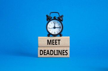 Meet Deadlines symbol. Concept word Meet Deadlines on wooden blocks. Beautiful blue background with alarm clock. Business and Meet Deadlines concept. Copy space