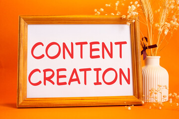 Content creation symbol. Concept words Content creation on beautiful wooden picture frame. Beautiful orange background with flower vase. Business and Content creation concept. Copy space.