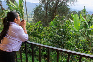 Woman drinking coffee while enjoying mountain view at coffee plantation