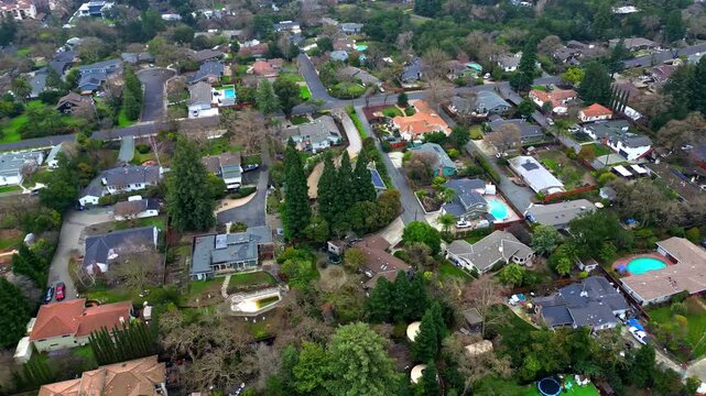 Suburban neighborhood aerial showing cul-de-sacs and rooftop textures under warm afternoon daylight