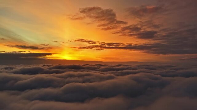 Soothing warm-toned cloud sea rolling beneath sunrise horizon as glowing colors stretch across sky