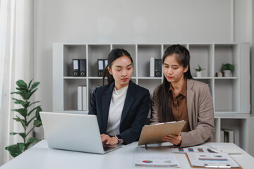 Business women collaborating on project using laptop and documents