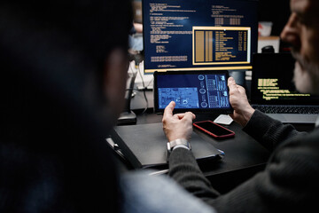 Middle aged Caucasian man holding digital tablet displaying technical schematics while sitting...